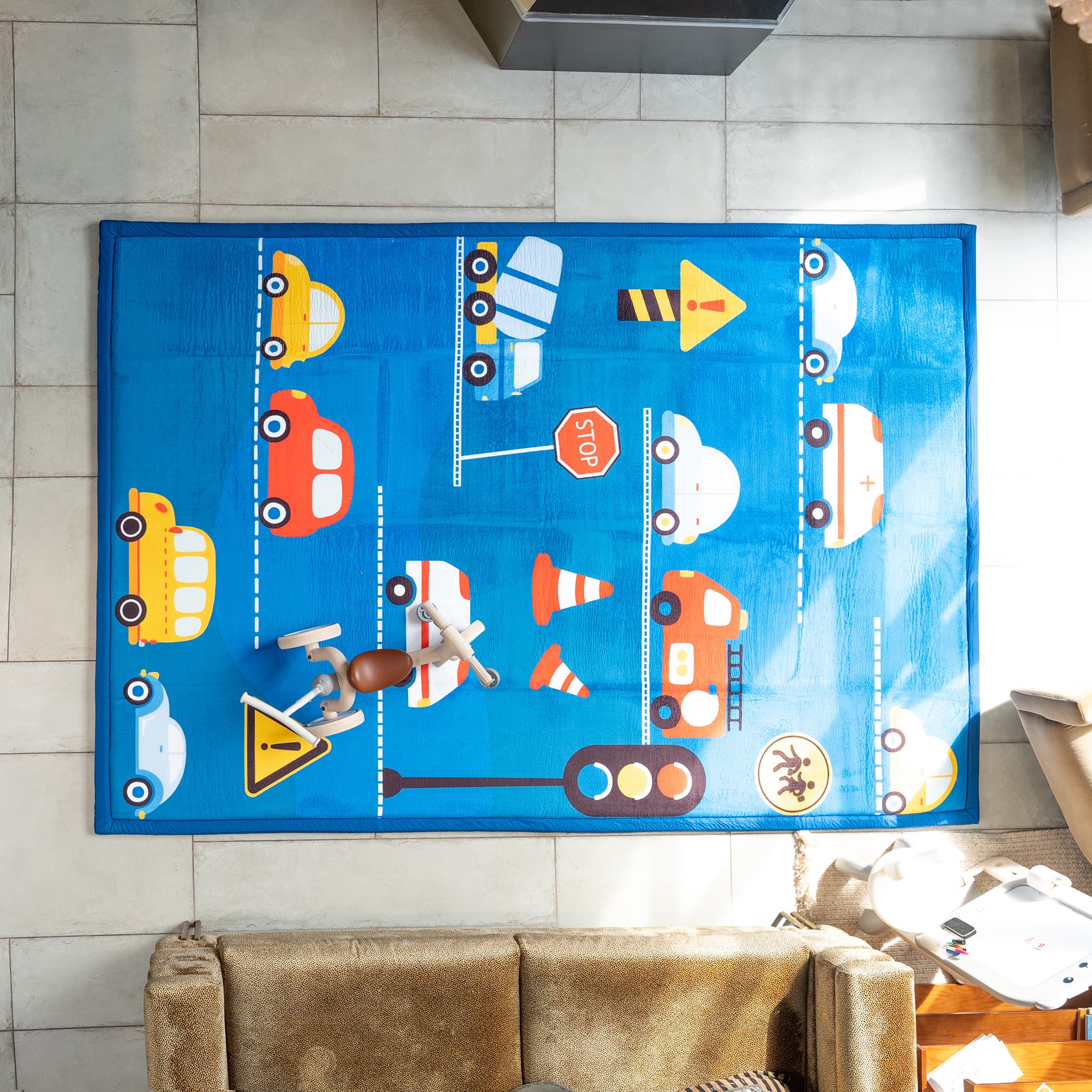 Children's play rug with transportation-themed design on a tiled floor.