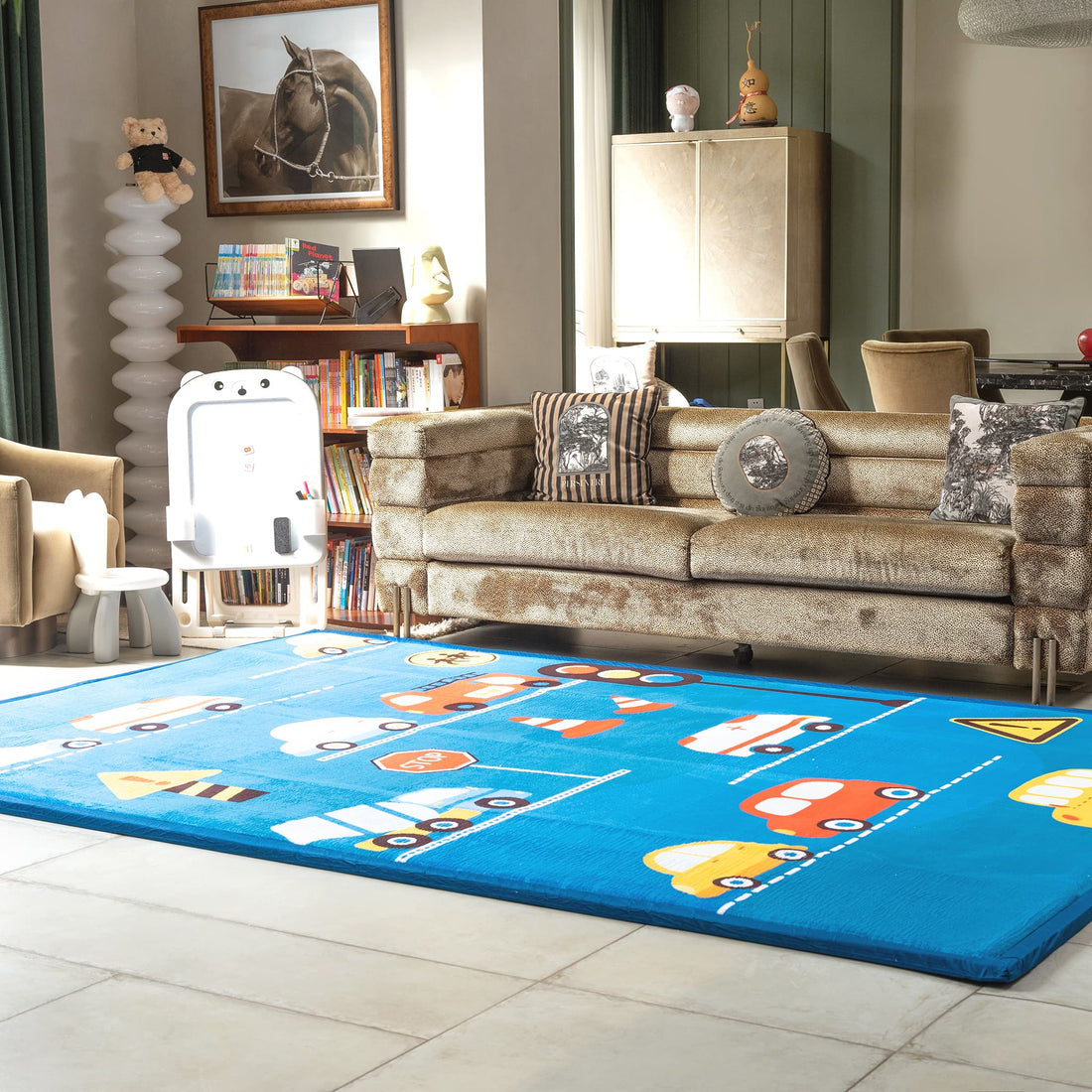 Children's room with a blue LuxKing Cloud rug featuring colorful car designs, a beige sofa, and toys.