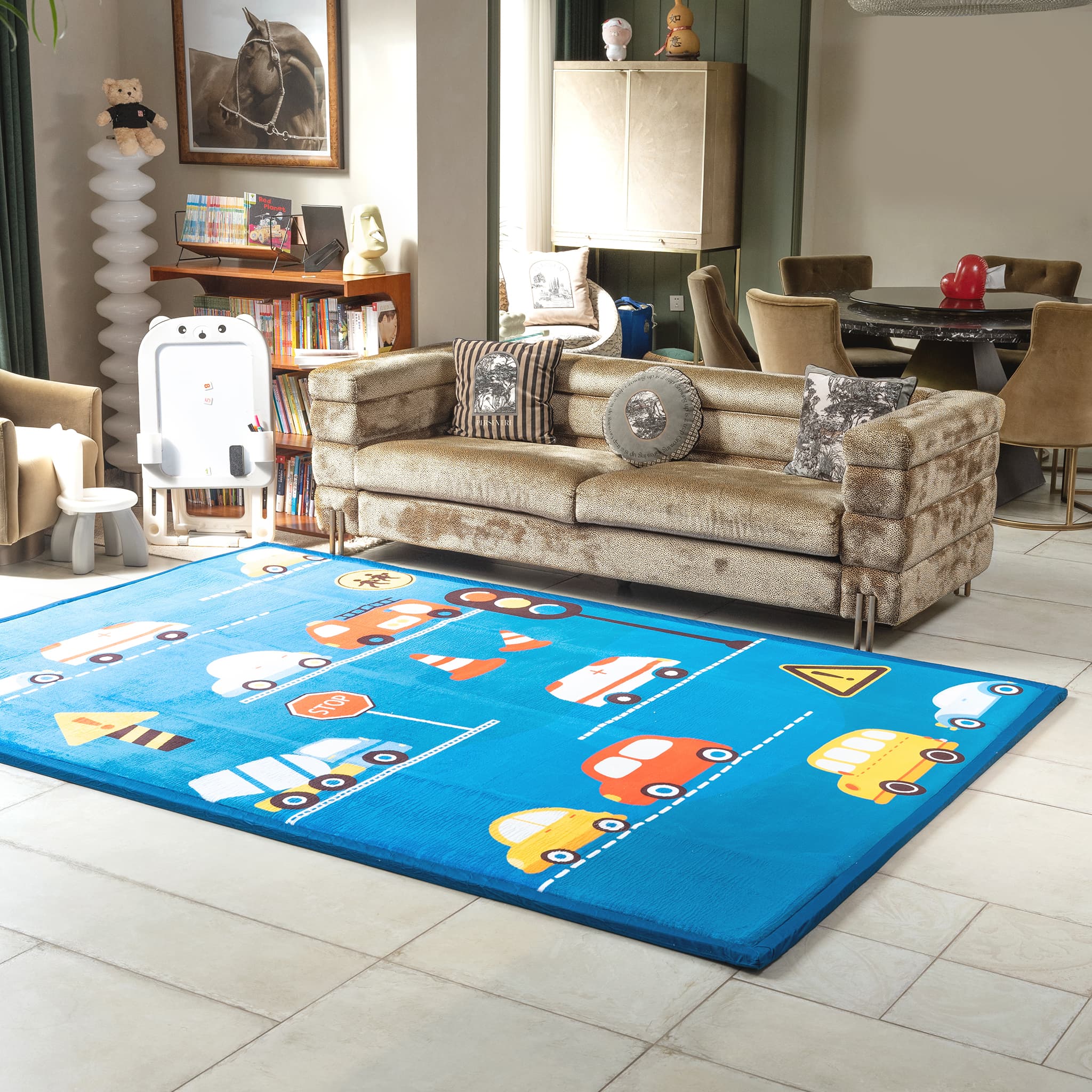 Living room with a blue LuxKing children's play rug featuring vehicle designs, a beige sofa, and various decor items.