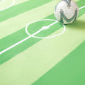 Soccer ball on a green surface with white lines resembling a soccer field