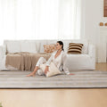 Woman sitting on a white couch with a striped rug in a bright living room.