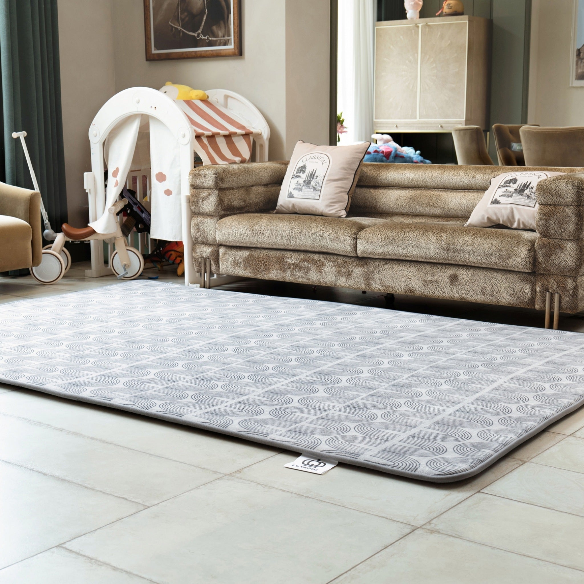 Living room with a patterned rug on the floor, sofa, and baby chair.