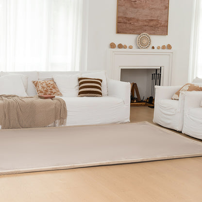Living room with white sofas, a beige rug, and decorative elements.