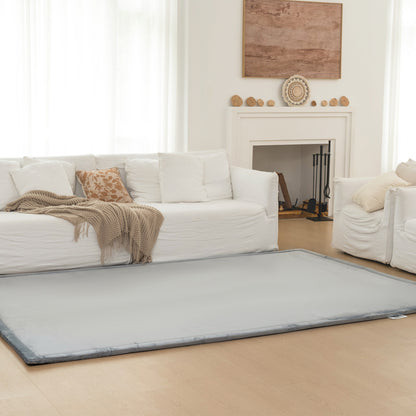 Living room with a large gray rug in front of a white sofa and fireplace.