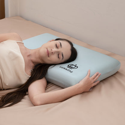 Woman lying on a bed with a light blue pillow featuring the Luxwine logo.