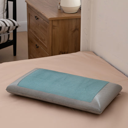 Teal and gray cooling pillow on a bed in a bedroom setting.