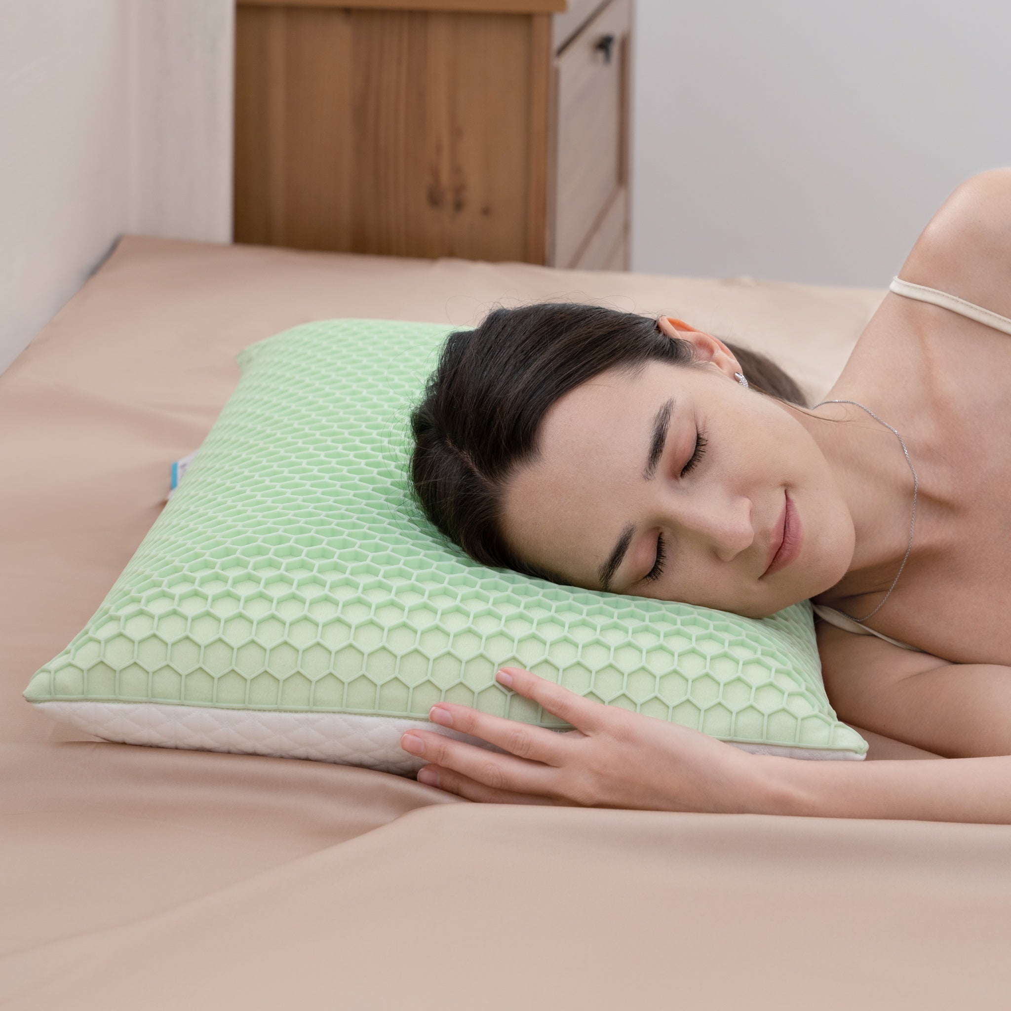 Woman lying on a bed with a green pillow, smiling.