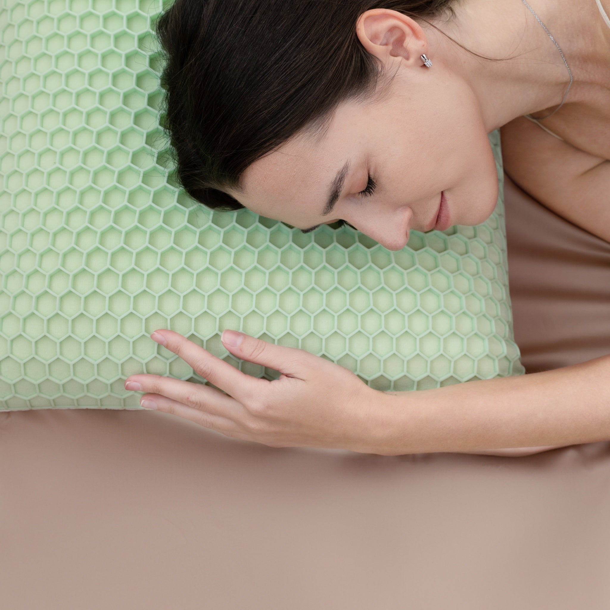 Woman lying on a green honeycomb pillow with a neutral background
