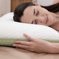 Woman lying on a white pillow with a green honeycomb pattern, smiling.