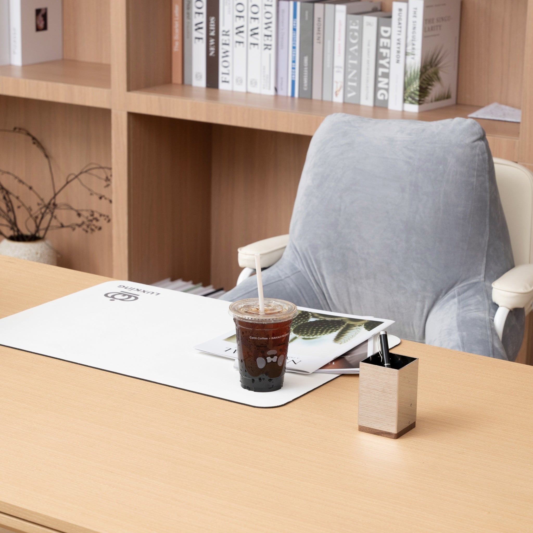 Desk setup with a cup of coffee, magazine, and office chair in an office setting.
