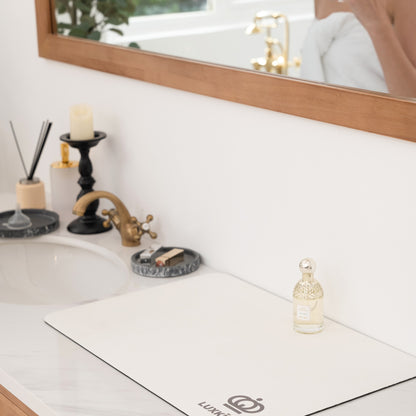 Bathroom counter with a bottle of L'Occitane product, candle, and soap.