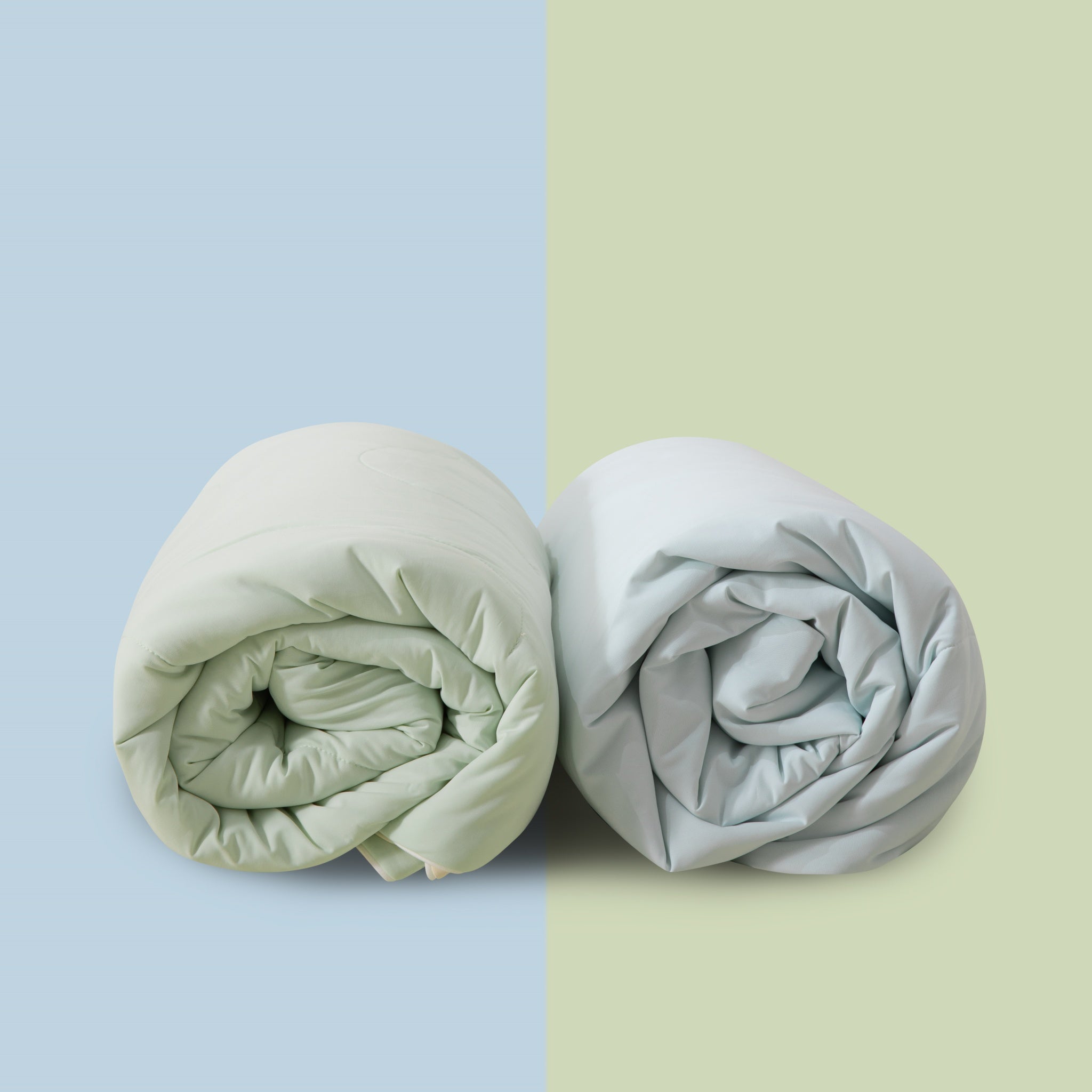 Two rolled-up blankets, one light green and one gray, on a two-tone blue and green background.