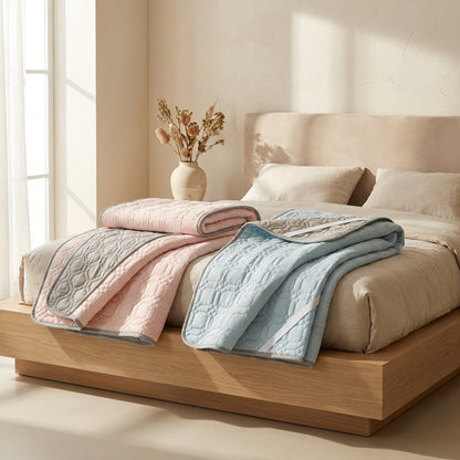 Bed with pink and blue textured blankets in a bright bedroom setting