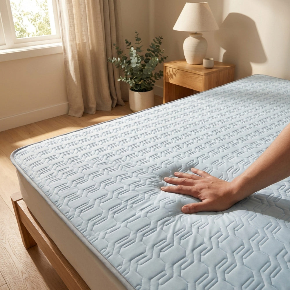 Person touching a mattress cover on a bed in a bedroom setting