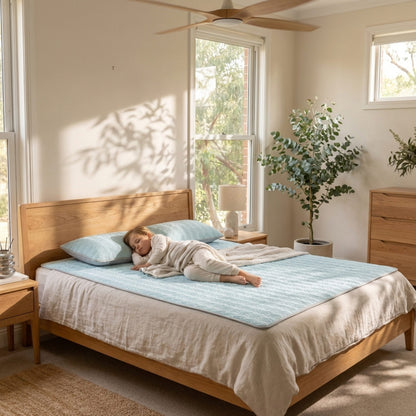 Child lying on a bed with light blue bedding in a bright bedroom