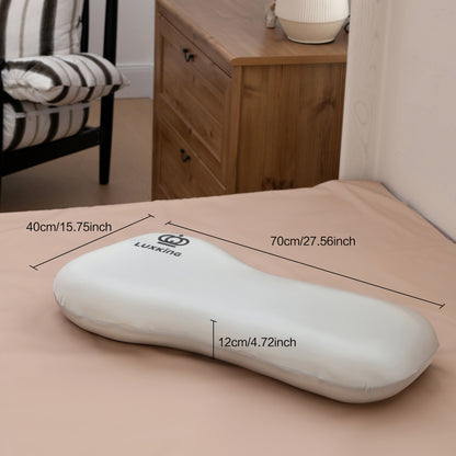 White ergonomic pillow with dimensions labeled on a bed in a bedroom setting