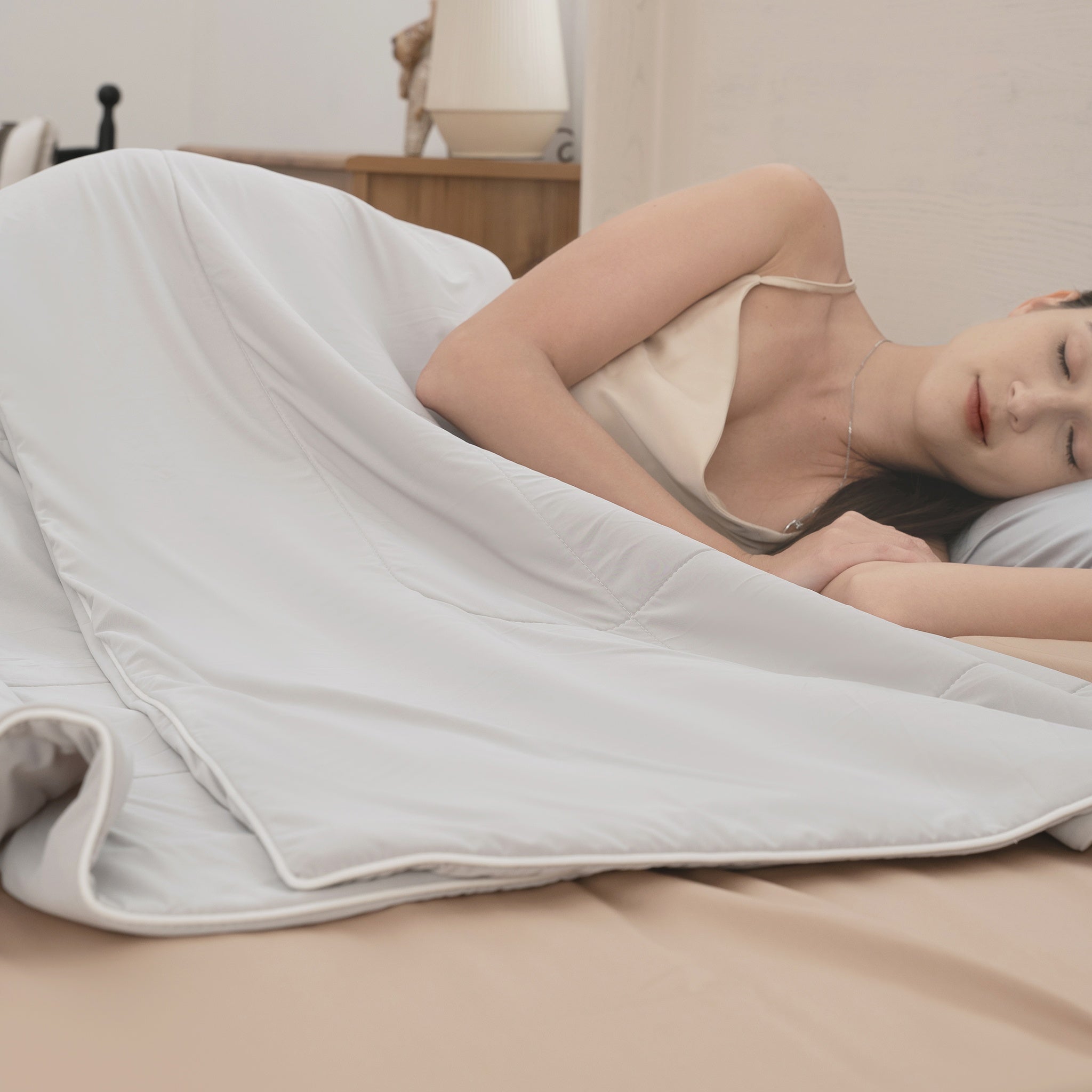 Woman lying on a bed under a white comforter in a bedroom setting