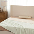 Bed with beige headboard and white bedding in a bedroom setting.