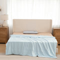 Bed with light blue comforter and beige headboard in a bedroom setting.
