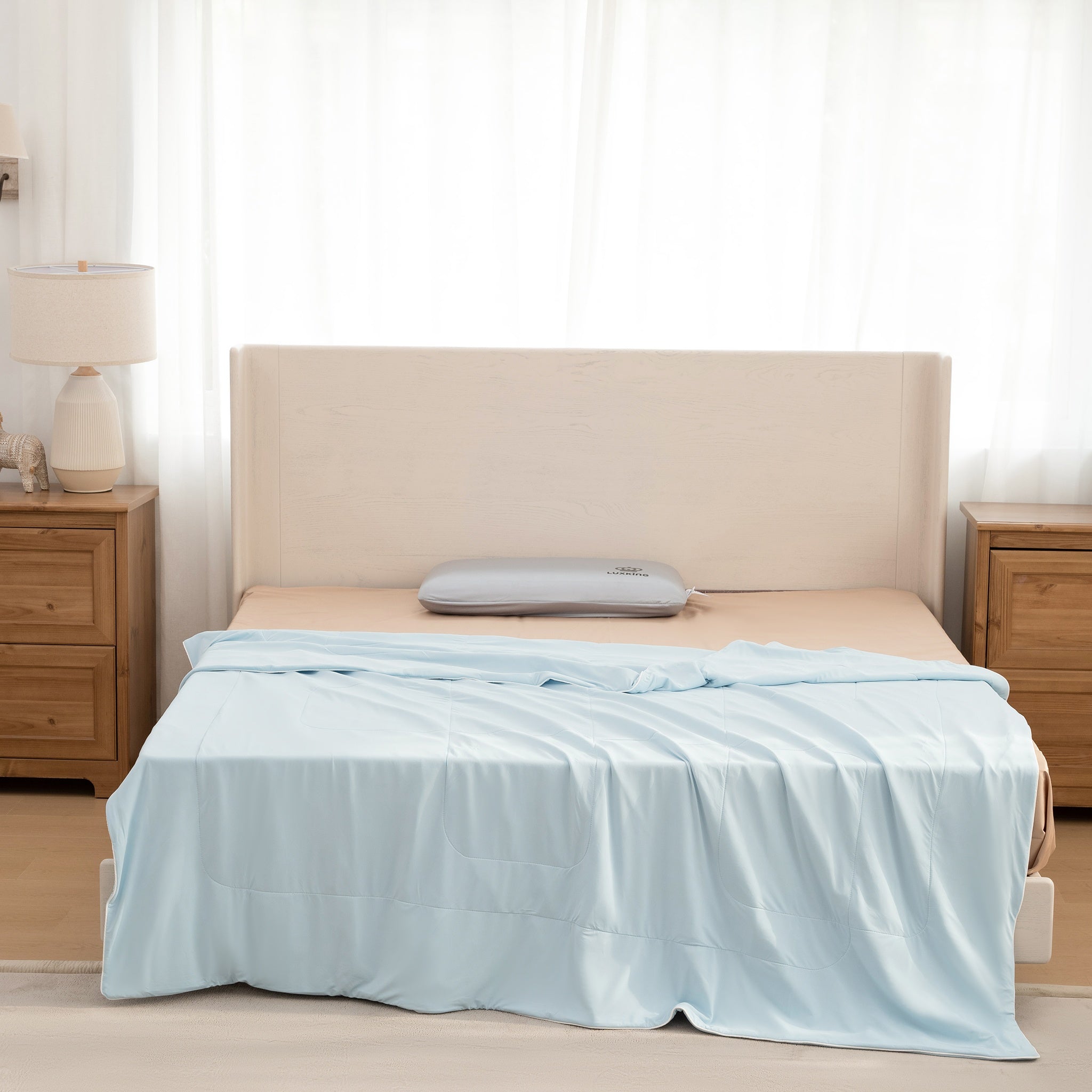 Bed with light blue comforter and beige headboard in a bedroom setting.